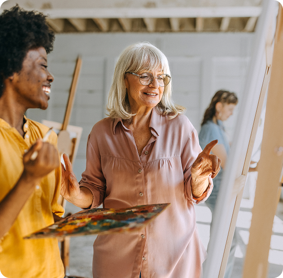 Image of two people smiling and painting together in an art studio
