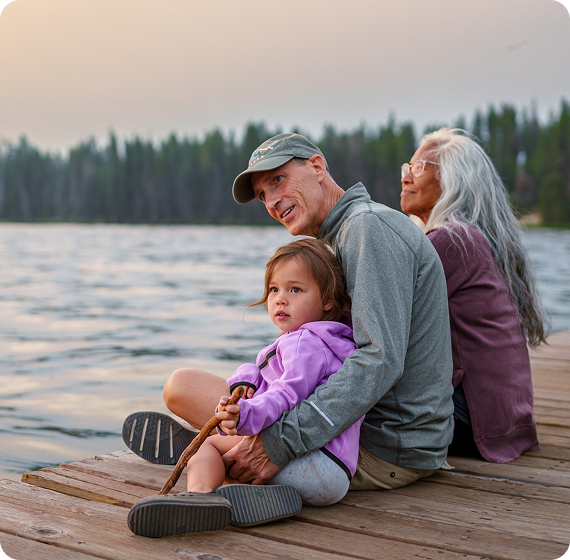 Image of family sitting on a dock by a lake, enjoying time together.