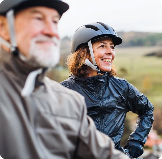 Image of two adults wearing helmets and smiling outdoors during a bike ride.
