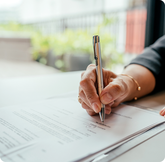 Image of a hand signing a document with a pen.