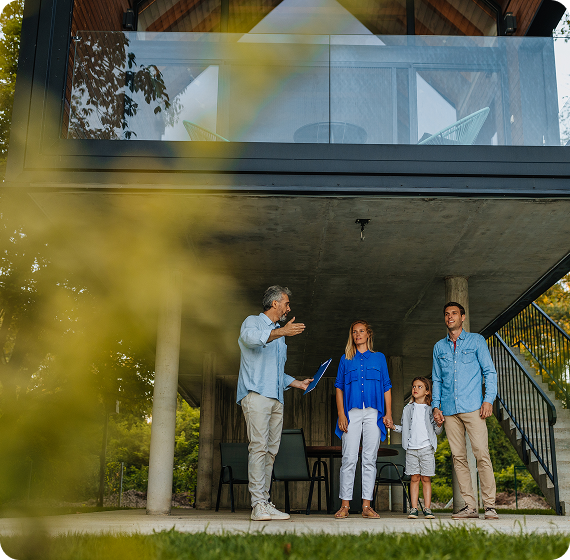 Image of a real estate agent talking with a family outside a modern home.