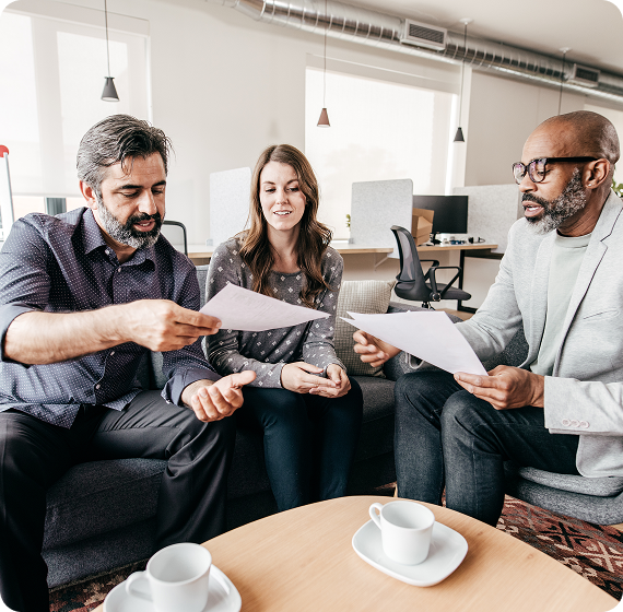 Image of three people reviewing documents together during a financial planning meeting.