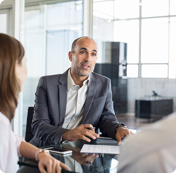 Image of financial advisor discussing documents with clients in a modern office.