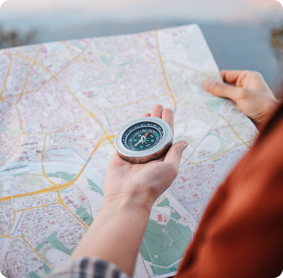 Image of person holding a compass over a folded map while planning a route.