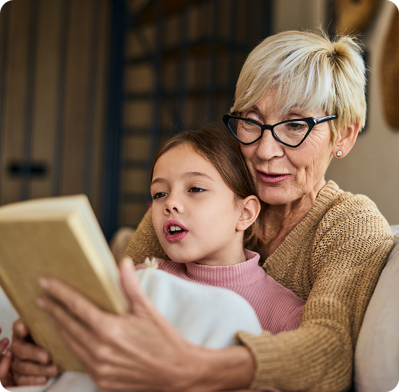 Image of grandparent reading with a child indoors.