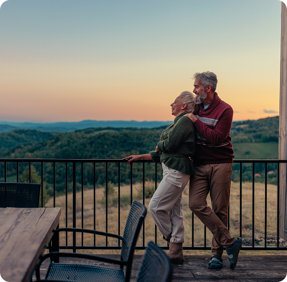 Image of older couple looking out on a balcony at sunset.