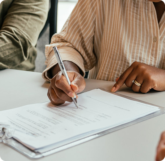 Image of person signing documents at a table during a meeting.