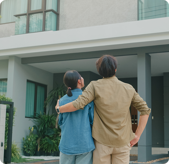 Image of two people standing arm in arm, looking at a modern home exterior.