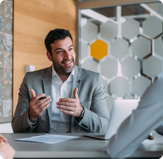 Image of financial advisor speaking and gesturing while meeting with clients at a table.