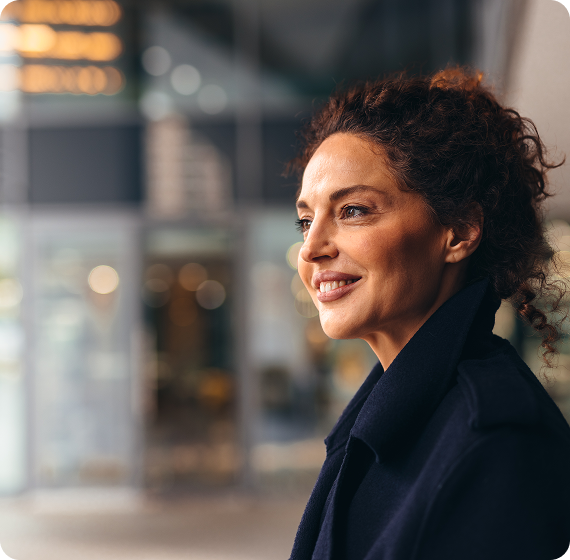 Image of woman smiling thoughtfully while looking ahead in a modern indoor space.