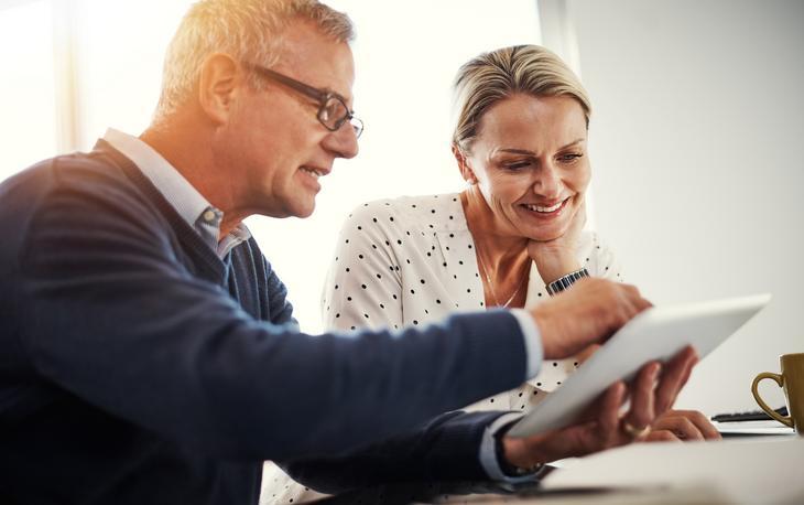 Two people discuss while looking at a tablet.