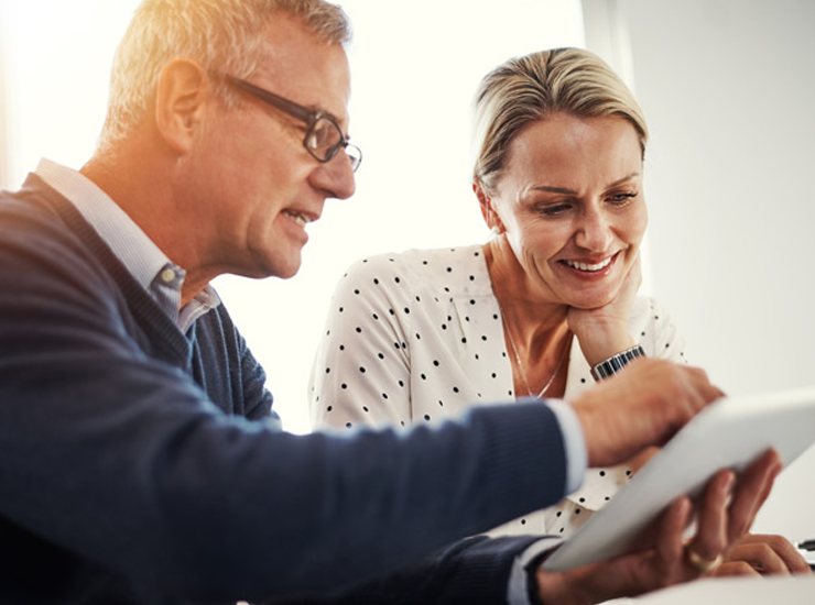 Two people discuss while looking at a tablet.